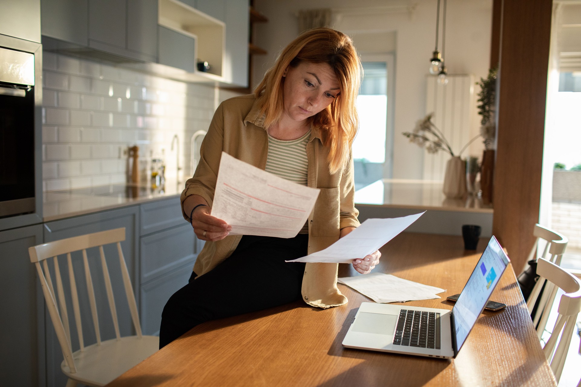 Young woman going over her finances at home while using her laptop Young woman going over her finances at home while using her laptop